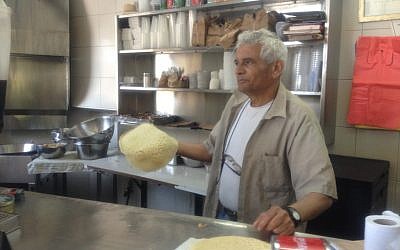 Motti Maabari with a freshly pan-fried lachluch in hand (Photo credit: Mitch Ginsburg/ Times of Israel)