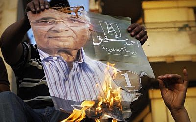Supporters of the Muslim Brotherhood's candidate Mohammed Morsi burn one of Ahmed Shafiq's election posters in Tahrir Square on Tuesday. (photo credit: Amr Nabil/AP)
