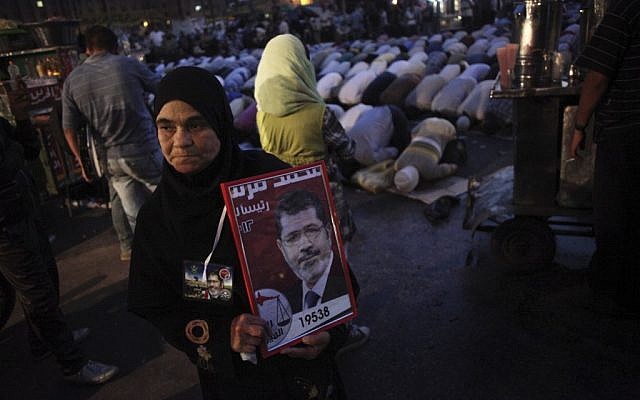An Egyptian woman holds a banner with the face of Muslim Brotherhood presidential candidate Mohamed Morsi in Tahrir Square in Cairo, Egypt, Thursday, 21 June (photo credit: AP/Manu Brabo)