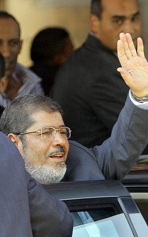 Egypt's President-elect Mohammed Morsi waves to his supporters following Friday prayers at Al-Azhar mosque in Cairo Friday (photo credit: Amr Nabil/AP)