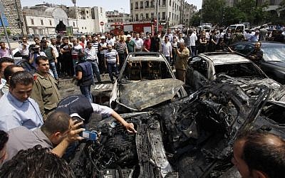 Syrians inspect burned cars at the site of a blast in the capital city, Damascus, Thursday. Opposition groups state Thursday was one of the bloodiest days since the Syrian uprising against President Basher Assad began. (photo credit: Muzaffar Salman/AP)