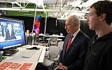 Former President Shimon Peres works on his Facebook page with Mark Zuckerberg, founder of Facebook, looking on (photo credit: Moshe Milner/GPO/Flash90)