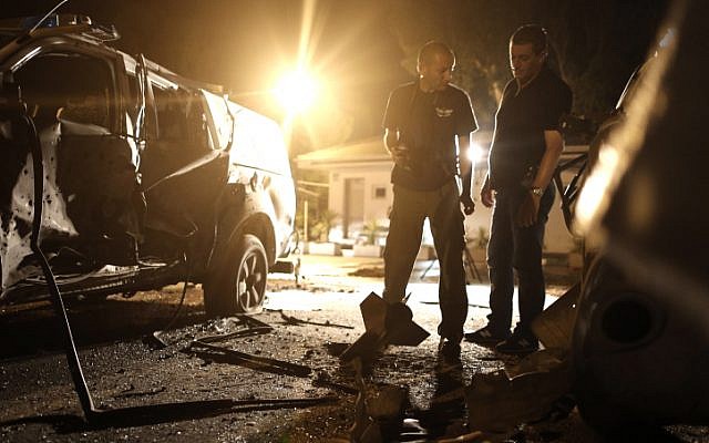Police officers examine the scene of a Kassam rocket launched from the Gaza Strip which hit a border patrol base near kibbutz Yad Mordechai on Tuesday (photo credit: Tsafrir Abayov/Flash90)