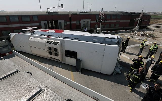 Firemen and emergency workers stand next to a damaged bus at the site of an accident between a bus and a train near Nitzan, Friday (photo credit: Tsafrir Abayov/Flash90)Firemen and emergency workers stand next to a damaged bus at the site of an accident between a bus and a train near Nitzan, Friday (photo credit: Tsafrir Abayov/Flash90)