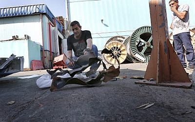 Men examine a rocket fired by Gaza terrorists that landed in Sderot's industrial zone in June (photo credit: Tsafrir Abayov/Flash90)