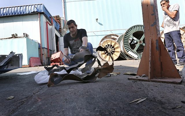 Men examine a rocket fired by Gaza terrorists that landed in Sderot's industrial zone in June (photo credit: Tsafrir Abayov/Flash90)