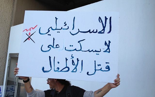 A sign in Arabic reads 'Israelis are not silent on killing of children' (photo credit: Elhanan Miller/Times of Israel)