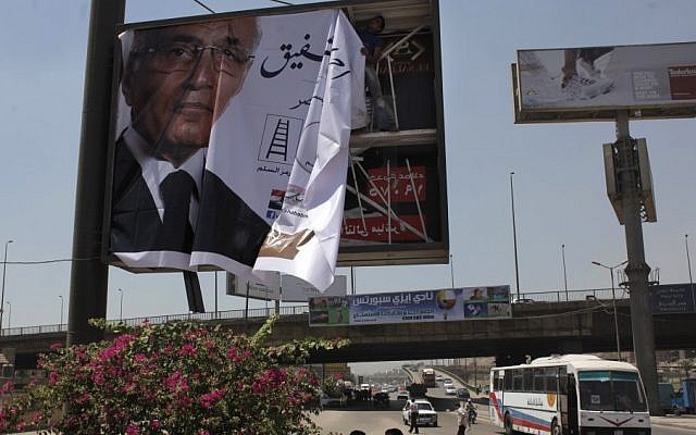 A poster for candidate Ahmed Shafiq being put up in Cairo this week. (photo credit: AP/Nasser Nasser)