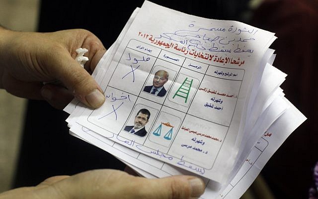 A man holds a ballot reading 'Down with the military regime' (photo credit: AP/Amr Nabil)