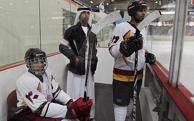 An Emirati organizer and two Omani hockey players watch a match with Kuwait in Abu Dhabi, United Arab Emirates (photo credit: AP/Kamran Jebreili)