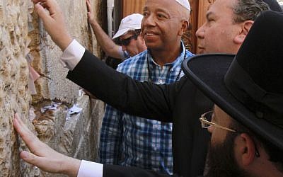 Hip hop mogul Russell Simmons touches stones of the Western Wall in Jerusalem's Old City, Thursday (photo credit: Blake Sobczak/AP)