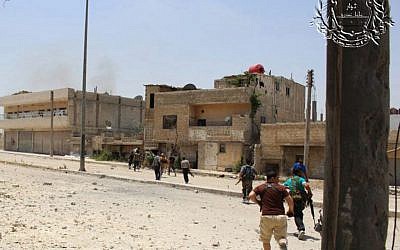 Syrian rebels hold their weapons as they cross a damaged street during clashes with Syrian troops in Homs, June 2012 (photo credit: AP/The Rebels Battalion of Baba Amro)