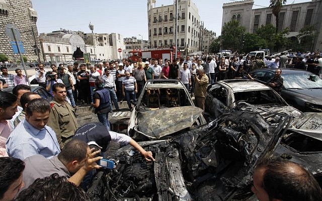 Syrians inspect burned cars at the site of a blast in Damascus. (photo credit: Muzaffar Salman/AP)