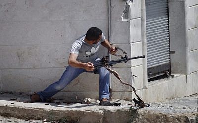 A Free Syrian Army fighter fires his weapon during clashes with Syrian troops near Idlib, Syria Friday. (photo credit: AP)