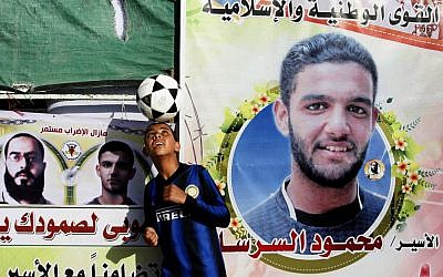 A Palestinian boy plays with a football in front of banners forming part of a protest tent in solidarity with Palestinian prisoner Mahmoud Sarsak last week. (photo credit: Abed Rahim Khatib/Flash 90)