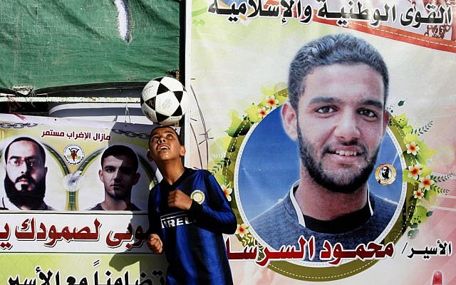 A Palestinian boy plays with a football in front of banners forming part of a protest tent in solidarity with Palestinian prisoner Mahmoud Sarsak last week. (photo credit: Abed Rahim Khatib/Flash 90)
