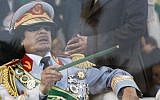Former Libyan leader Moammar Gaddafi gestures with a green cane as he takes his seat behind bulletproof glass for a military parade in Green Square, Tripoli, Libya in 2009 (photo credit: AP/Ben Curtis)