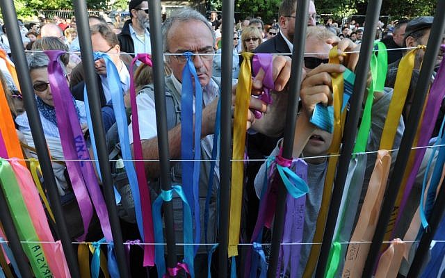 People attach ribbons with Jewish names onto the fence of a former Jewish orphanage during commemorations marking the 70th anniversary of the first transport of Jews from the Warsaw Ghetto to the Treblinka death camp during World War II (photo credit: AP/Alik Keplicz)