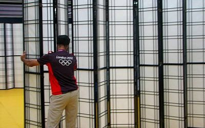 An Olympic worker places a barrier between Israeli and Lebanese athletes (photo credit: courtesy of the Israeli Olympic Committee)