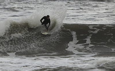An Israeli surfer rides the waves off Ashkelon (Photo credit: Tsafrir Abayov/Flash90)