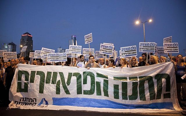 Thousands rally in Tel Aviv on Saturday night behnd a banner that reads "Suckers' Camp" (photo credit: Tali Mayer/Flash90)