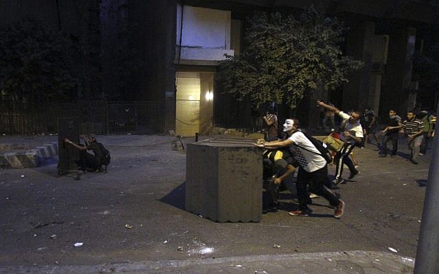 Protesters take cover behind makeshift barricades and throw rocks at Egyptian riot police during clashes outside the Syrian Embassy in Cairo, on July 18, 2012. (photo credit: Ahmed Gomaa/AP)