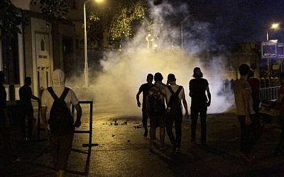 Protesters walk through a cloud of tear gas during clashes with Egyptian riot police outside the Syrian embassy in Cairo on Wednesday, July 18, 2012. (photo credit: Ahmed Abdel-Fattah/AP)