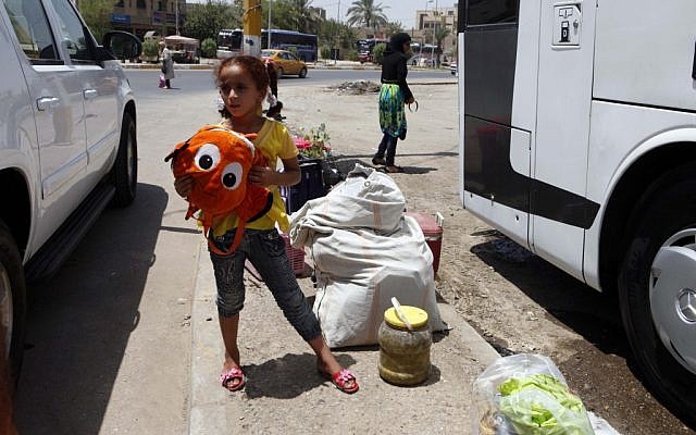 Layla Fadhil, an Iraqi refugee, stands with her family's belongings after her arrival from Syria in the Mansour neighborhood of Baghdad on Friday. (photo credit: AP/Karim Kadim)