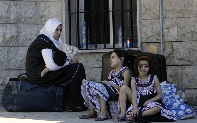 A Syrian woman sits with her children outside the Lebanese immigration office at the Masnaa border post shortly after crossing from Syria to Majdal Anjar, Lebanon on July 23. (photo credit: AP/Bilal Hussein)