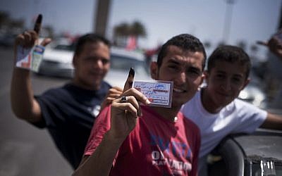 Libyan men hold their elections ID cards while celebrating election day in Tripoli on July 7, 2012. (photo credit: Manu Brabo/AP)