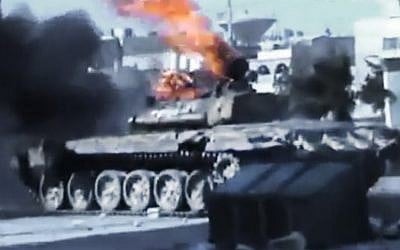 This image taken from an amateur video shows a Syrian military tank on fire during clashes with Syrian government troops in Aleppo on Monday. (photo credit: Ugarit News/AP video)