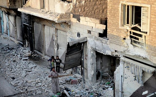 In this citizen journalism image taken on Saturday, a Syrian family stand in the rubble of destroyed houses in Maarat al-Numaan on the eastern edge of Idlib province, northern Syria. (Photo credit: AP/Edlib News Network ENN)