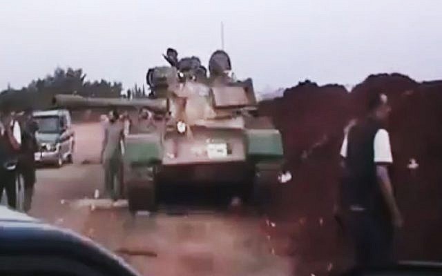 This image  released by the Ugarit News purports to show Free Syrian Army soldiers standing near a military tank in Anadan, 16 kilometers (10 miles), from Aleppo, Syria (photo credit: AP/Ugarit News via AP video)