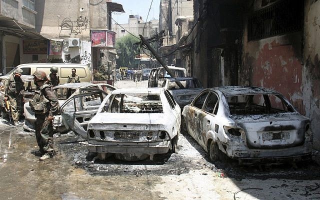 Syrian soldiers stand next to burned cars after they regained control of the district of Midan, in the southern part of Damascus, Syria, Friday, July 20, 2012. (photo credit: Bassem Tellawi/AP) Syrian soldiers stand next to burned cars after they regained control of the district of Midan, in the southern part of Damascus, Syria, Friday, July 20, 2012. (photo credit: Bassem Tellawi/AP)
