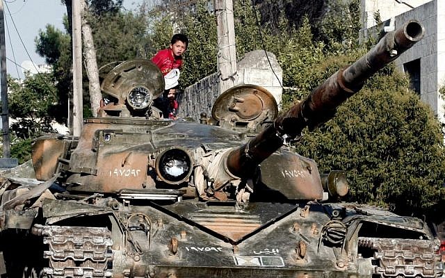 A Syrian boy sits atop a damaged military tank at the border town of Azaz, some 20 miles (32 kilometers) north of Aleppo last month (photo credit: AP/Turkpix) A Syrian boy sits atop a damaged military tank at the border town of Azaz, some 20 miles (32 kilometers) north of Aleppo last month (photo credit: AP/Turkpix)