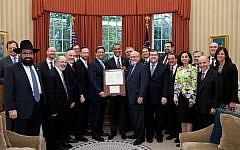 President Obama, flanked by Nathan Diament, left, and Dr. Simcha Katz of the Orthodox Union, displays the framed reproduction of President George Washington’s letter to the Jewish community of Newport, R.I., that he was given at the conclusion of his Oval Office meeting with Orthodox Jewish leaders last July. (photo credit: Official White House Photo by Pete Souza/JTA)