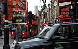 A woman waits at a traffic light in one of London's busiest streets. (Photo credit: Gili Yaari/Flash90)