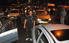 Protesters carry signs as they block traffic on Tel Aviv's Ayalon freeway Sunday night (photo credit: Artiom Degel)