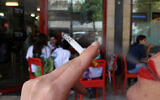 Illustrative photo of a woman smoking a cigarette outside an Israeli cafe. (Nati Shohat/Flash90)