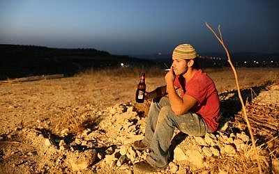 Smoking a cigarette and drinking beer on  the outskirts of the Havat Gilad settlement. Finance Minister Yuval Steinitz raised beer and cigarette prices overnight on July 25. (photo credit: Nati Shohat/Flash90)
