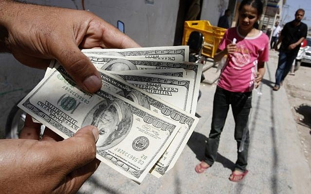 A Palestinian man displays money withdrawn from the Bank of Palestine in the Gaza Strip June, 2012 (photo credit: Abed Rahim Khatib/Flash90)