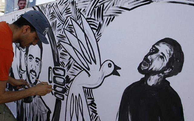 Palestinian painters paint murals of Mahmoud Sarsak (R) and other prisoners, in the southern Gaza Strip on June 10, 2012. Sarsak, a former member of the Palestinian National Soccer Team, was released after three-month hunger strike. (photo credit: Abed Rahim Khatib/Flash 90)