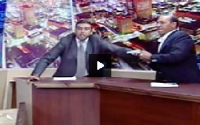 MP Shawabka (right) draws his gun, as the host tries to calm tempers, during a debate on Jordanian TV last week. (photo credit: YouTube screen capture) MP Shawabka (right) draws his gun, as the host tries to calm tempers, during a debate on Jordanian TV last week. (photo credit: YouTube screen capture)