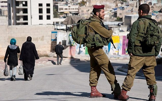 Israeli soldiers patrol among Palestinian pedestrians in Hebron