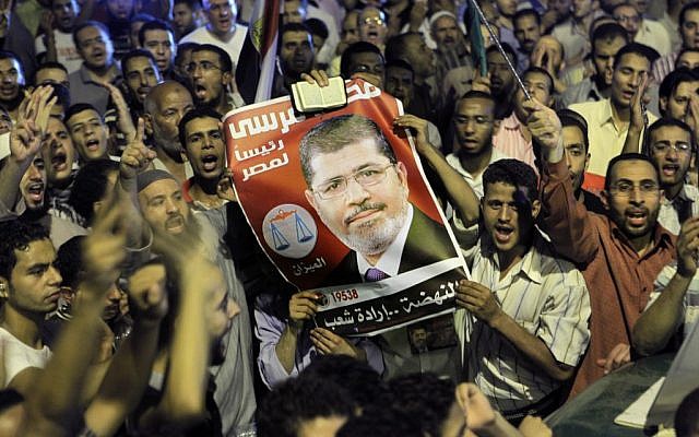 Thousands of supporters raise a poster of Egypt's Islamist President Mohammed Morsi as they celebrate in Tahrir Square in Cairo, late Sunday, Aug. 12, 2012. (photo credit: Amr Nabil/AP)