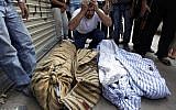 A Syrian man grieves over the bodies of four members of his family in Aleppo last year. (photo credit: AP Photo/ Khalil Hamra)