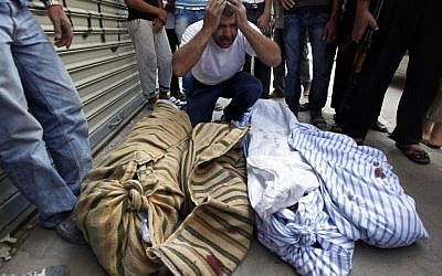 A Syrian man grieves over the bodies of four members of his family in Aleppo last year. (photo credit: AP Photo/ Khalil Hamra)
