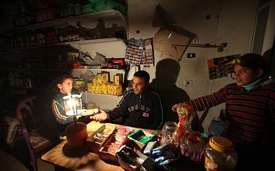 A Palestinian shopkeeper lights a gas lamp during a power cut at his shop in El-Shatea refugee camp western Gaza city in 2010 (photo credit: Wissam Nassar/Flash90)