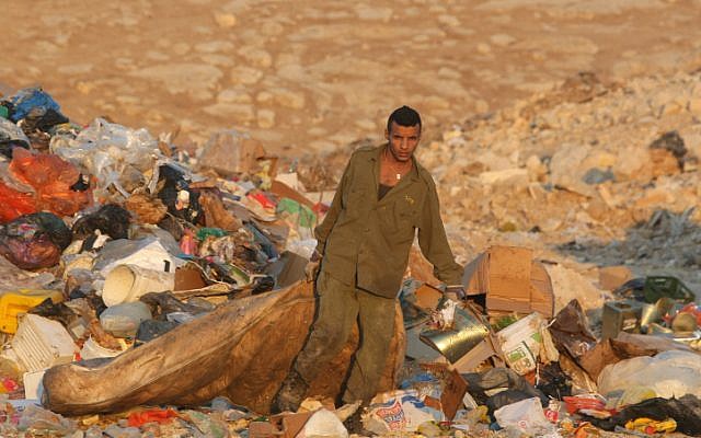 A Bedouin man with an IDF uniform drags a mattress as he looks for anything valuable at a garbage dump outside Jerusalem. (photo credit: Kobi Gideon/Flash90). A Bedouin man with an IDF uniform drags a mattress as he looks for anything valuable at a garbage dump outside Jerusalem. (photo credit: Kobi Gideon/Flash90).