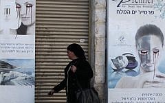 A woman walks past a vandalized poster in Jerusalem, December 6, 2011. (photo credit: Yossi Zamir/Flash90)